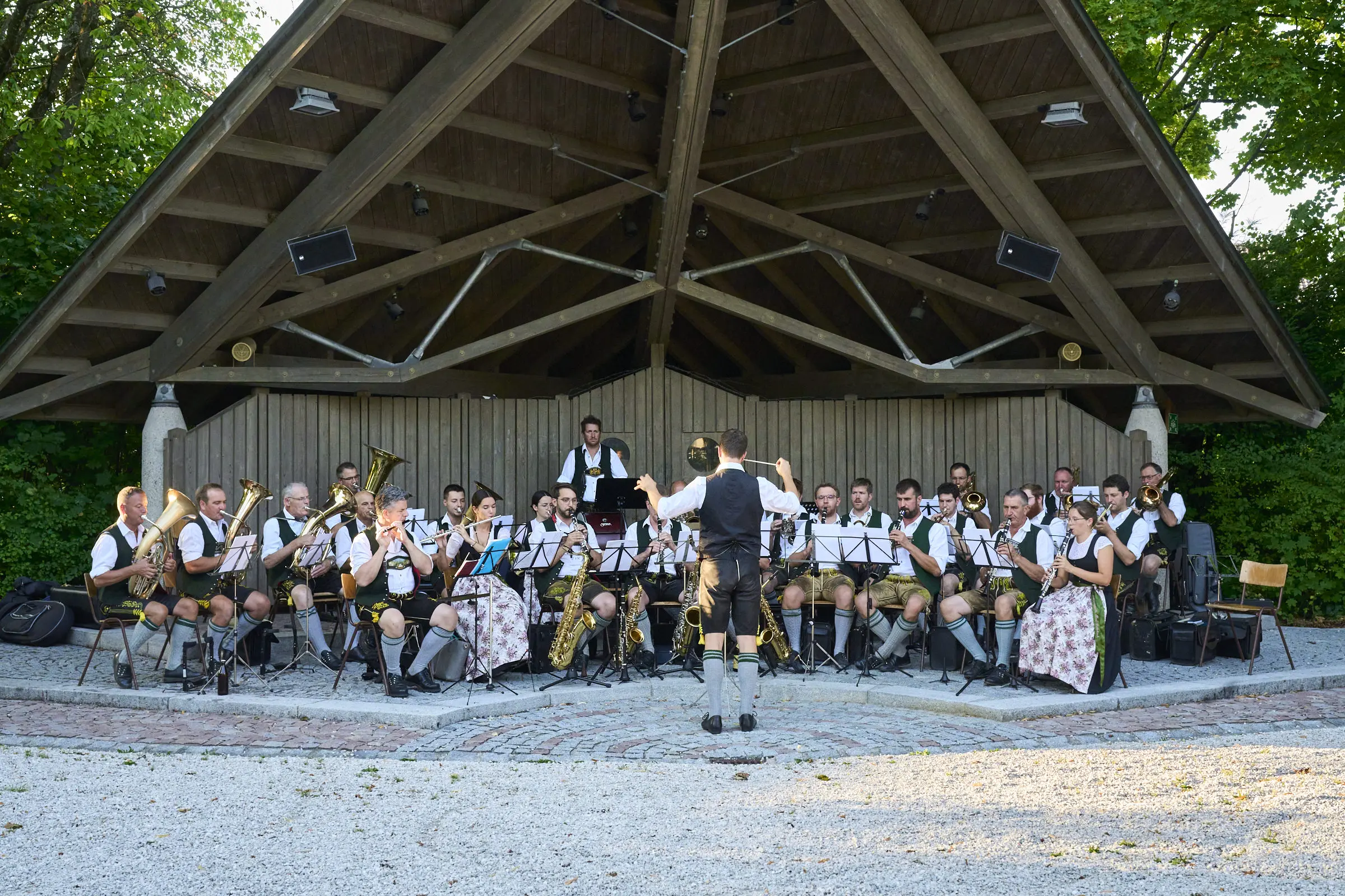 Blaskapelle in Tracht spielt unter einem Holzpavillon auf.