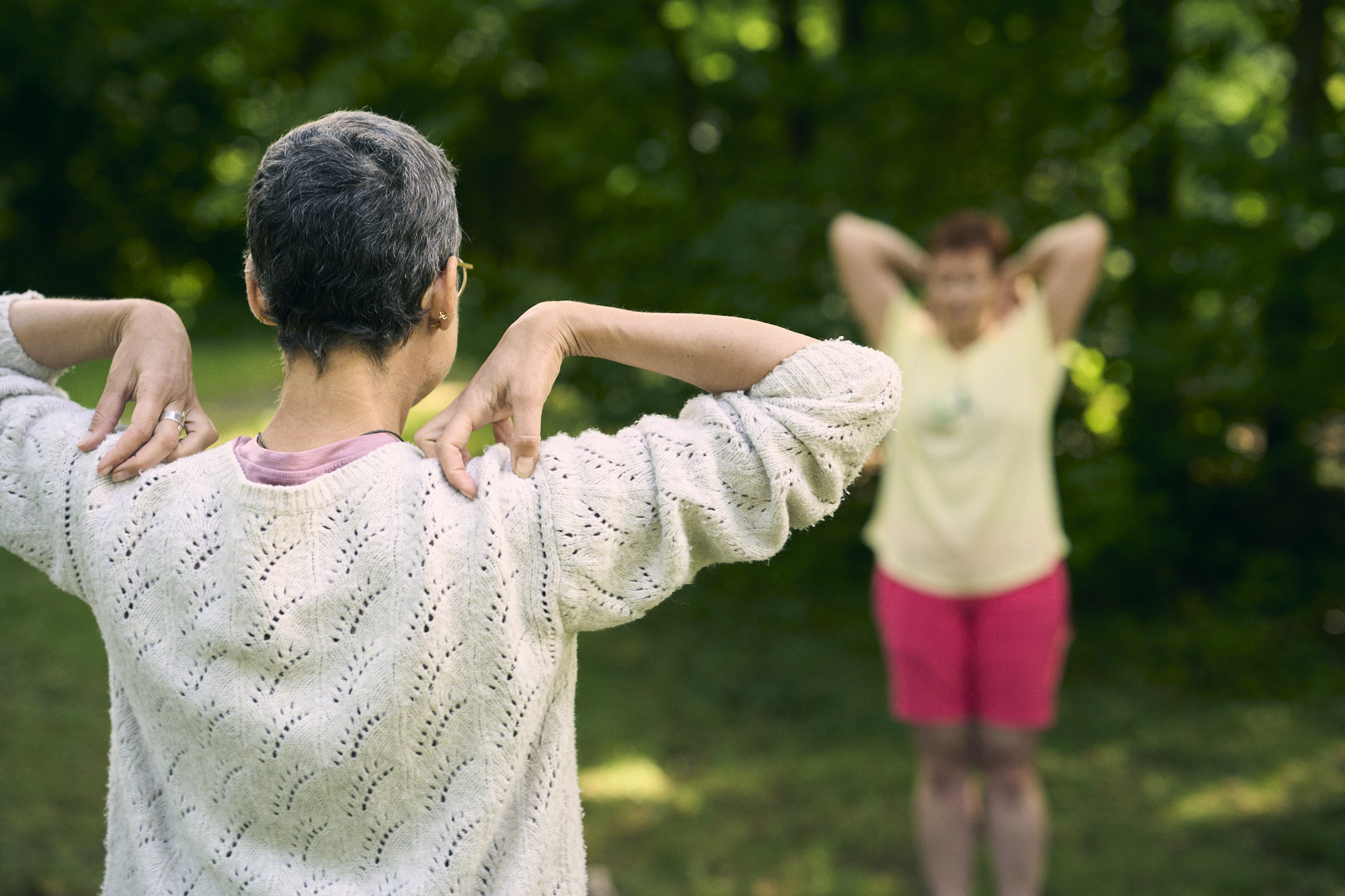 Zwei Frauen machen Dehnübungen im Freien.