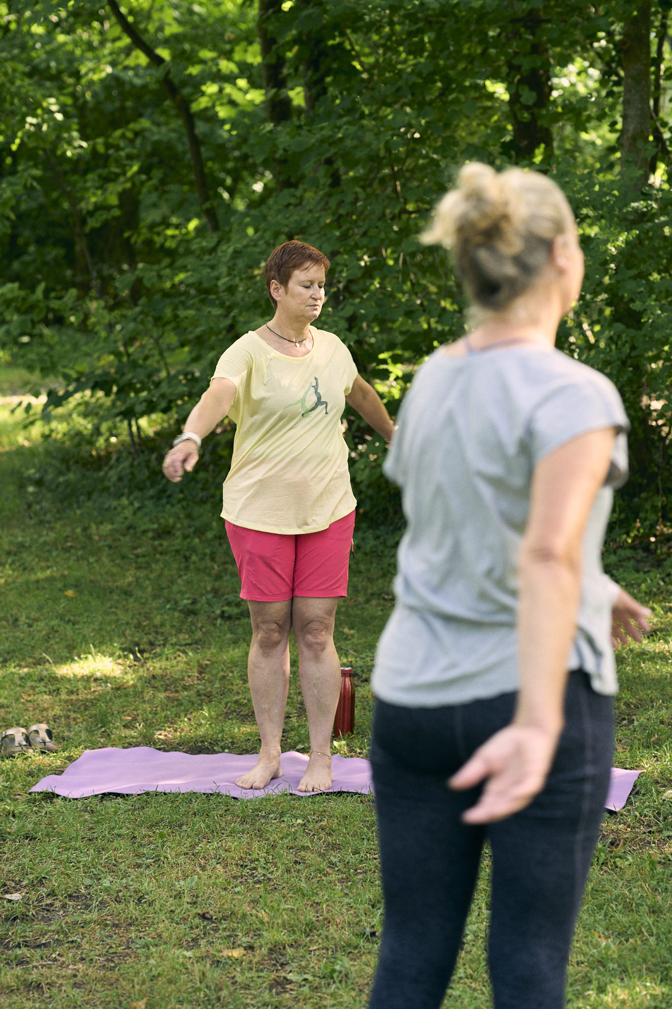 Frauen praktizieren Yoga im Freien auf Yogamatten im Gras.