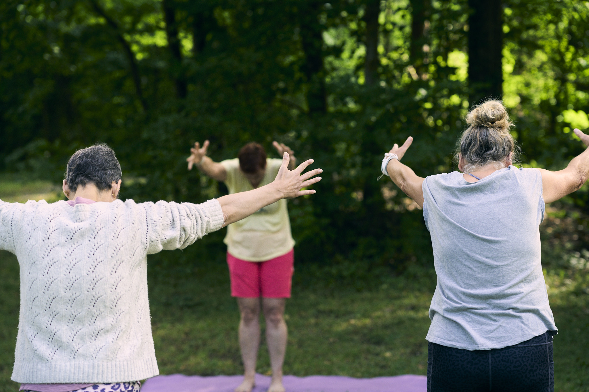 Drei Frauen praktizieren Yoga im Freien in einem Wald.