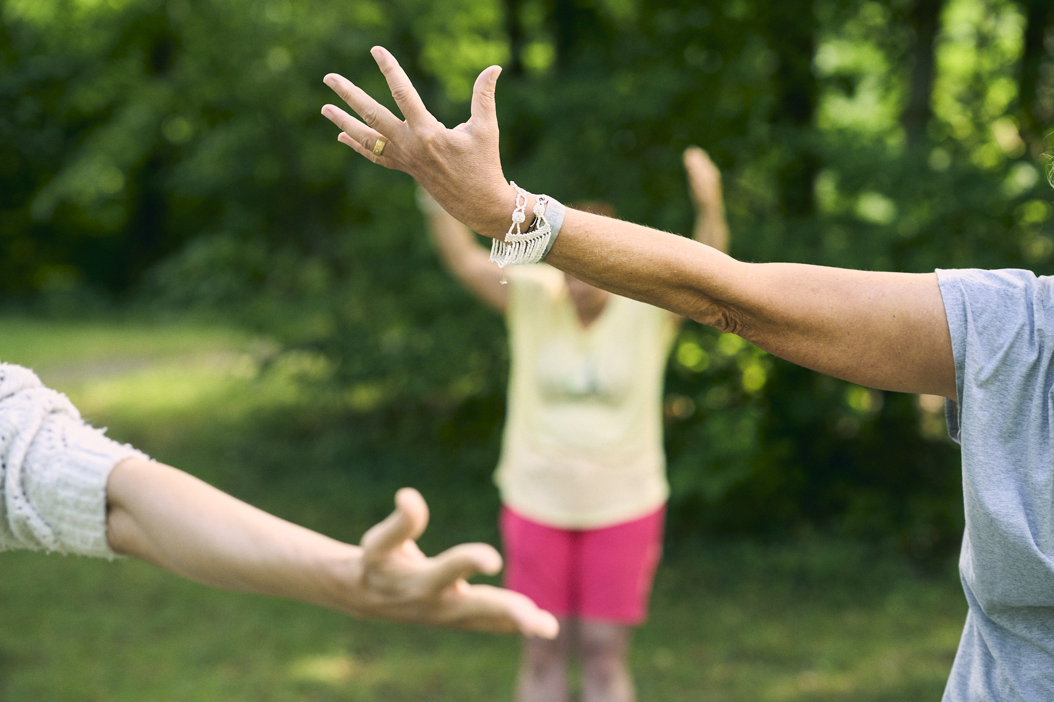 Personen praktizieren Tai Chi im Freien auf Grasfläche.