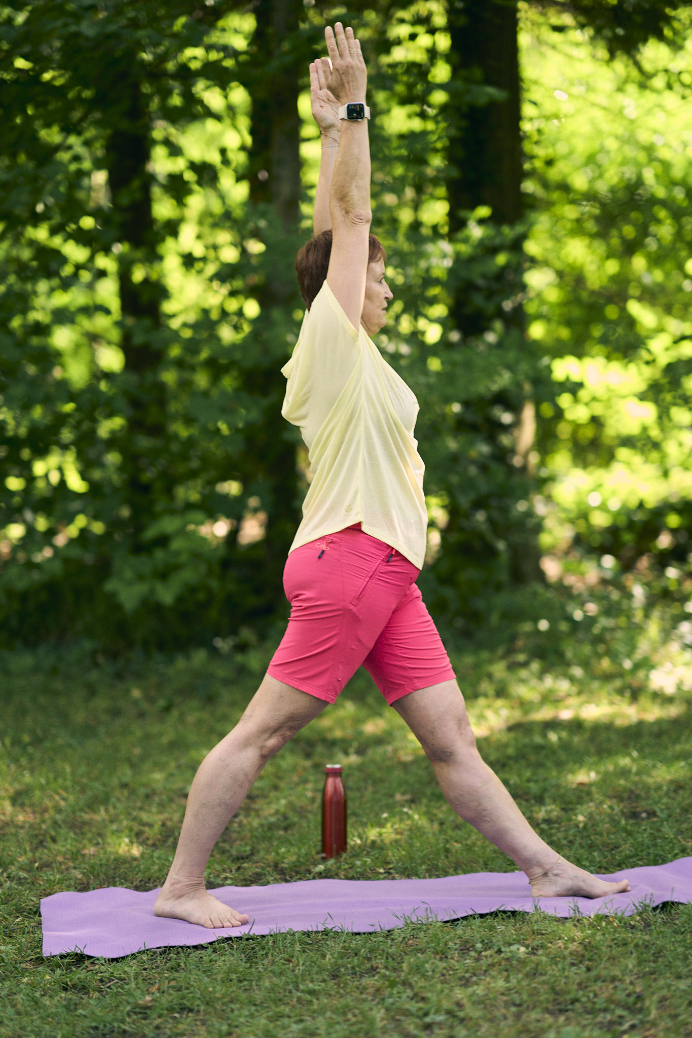 Ältere Frau in Ausfallschritt-Yoga-Pose im Freien.